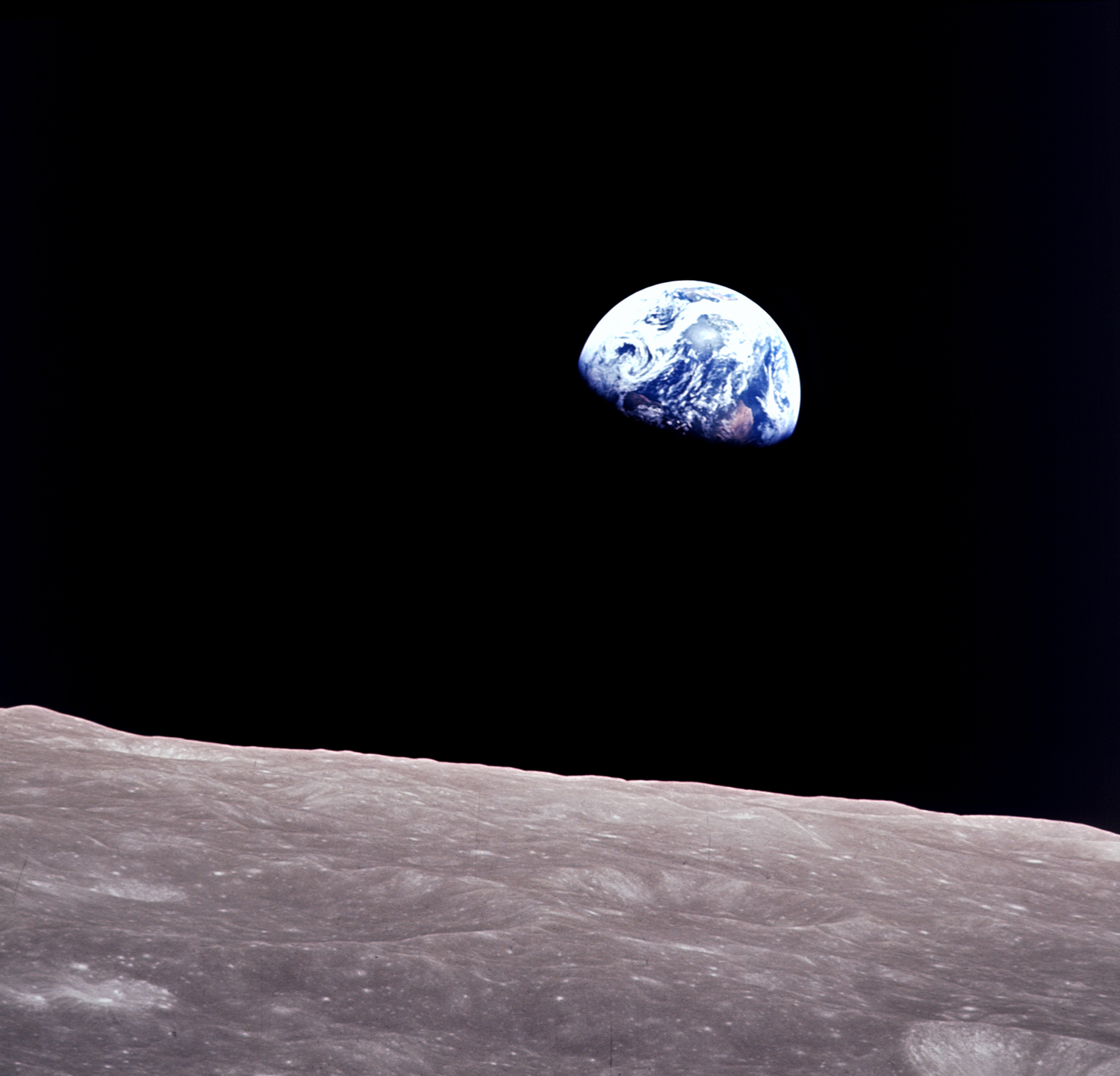 Esta vista de la Tierra tomada durante la órbita lunar del Apolo 8 muestra la Tierra flotando en el fondo y la superficie lunar en primer plano.  Es una de nuestras mejores imágenes espaciales.
