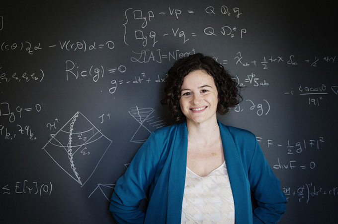Una foto de Elena Giorgi parada frente a una pizarra con ecuaciones matemáticas escritas con tiza blanca.